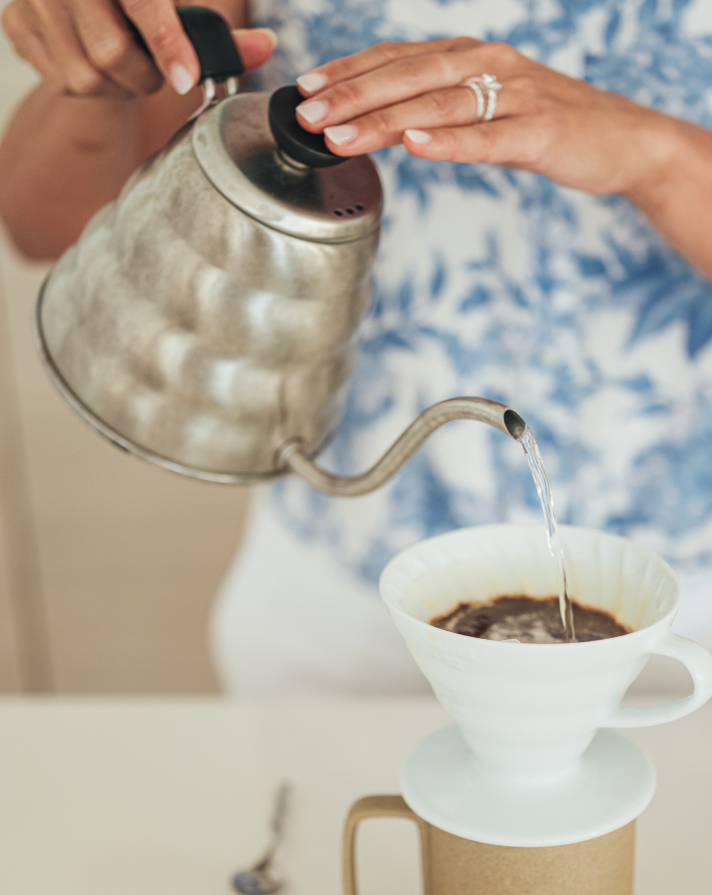 woman's hand pouring hot water into a tea cup